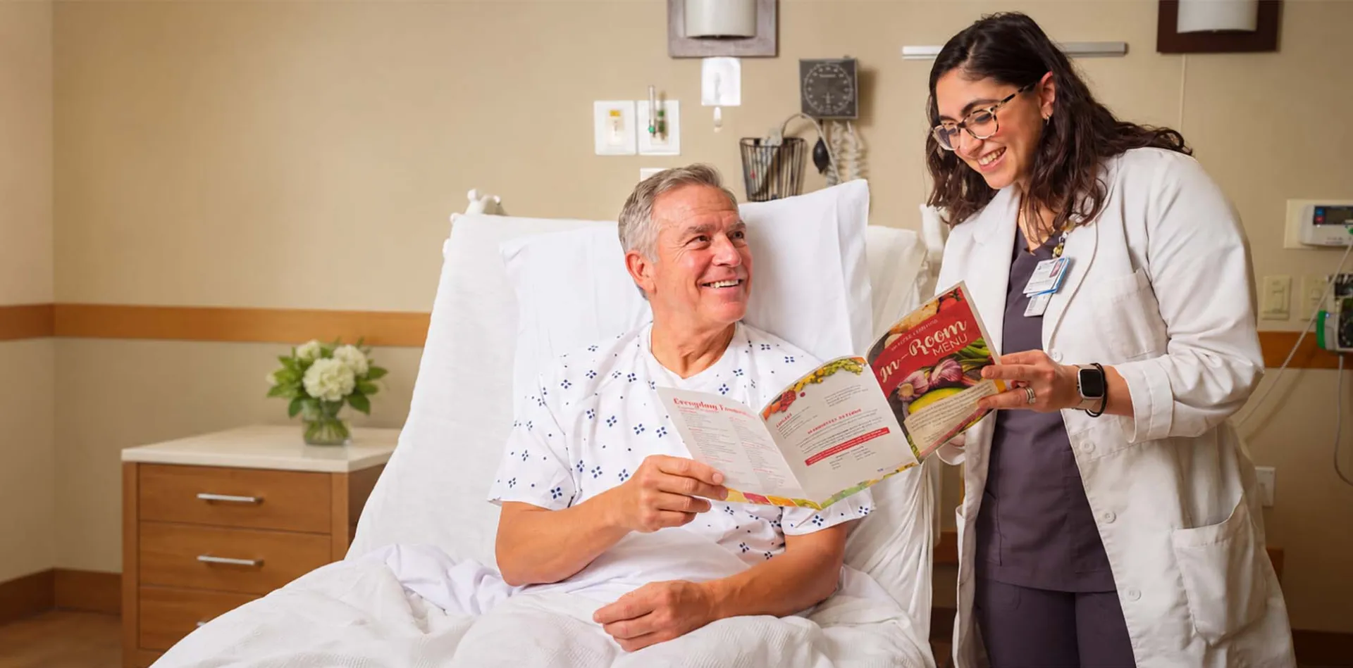 Dietitian reviewing a nutrition menu with an older patient in a hospital room.
