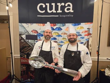 two chefs holding a big spoon