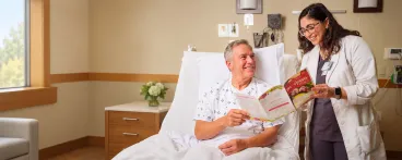 Dietitian reviewing a nutrition menu with an older patient in a hospital room.